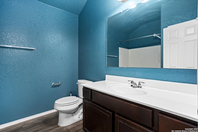 full bathroom with toilet, wood finished floors, vanity, and a textured wall