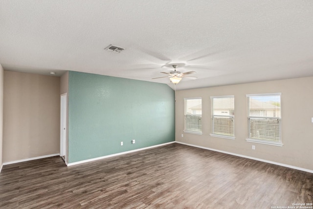 empty room with a textured ceiling, wood finished floors, baseboards, and a ceiling fan