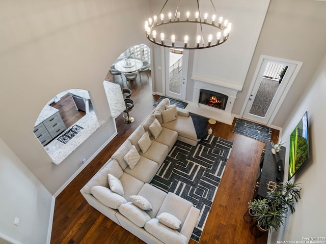 922 Split Fairway, San Antonio, TX 78260 - living room with a chandelier, a warm lit fireplace, wood finished floors, baseboards, and arched walkways