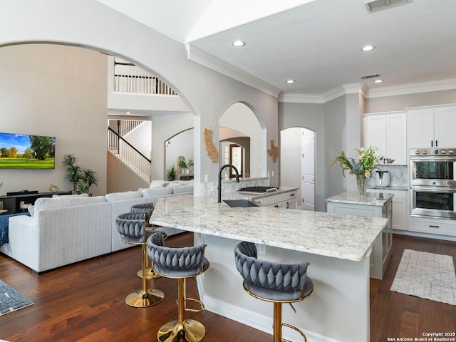922 Split Fairway, San Antonio, TX 78260 - kitchen featuring arched walkways, light stone countertops, stainless steel appliances, and a kitchen breakfast bar