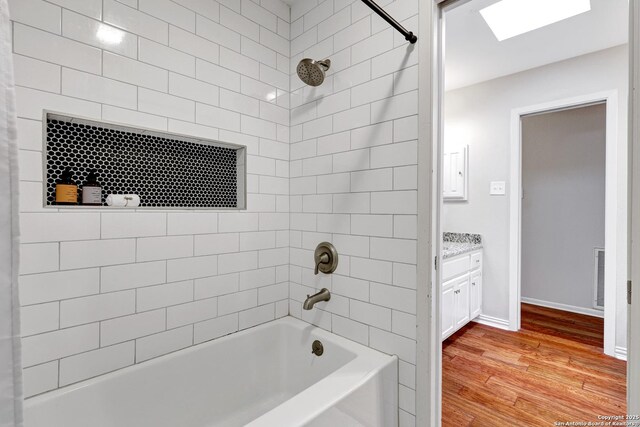 310 Twisted Wood, San Antonio, TX 78216 - bathroom with wood finished floors, washtub / shower combination, vanity, baseboards, and a skylight
