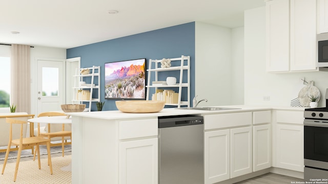 kitchen with white cabinets, light countertops, a peninsula, appliances with stainless steel finishes, and a sink