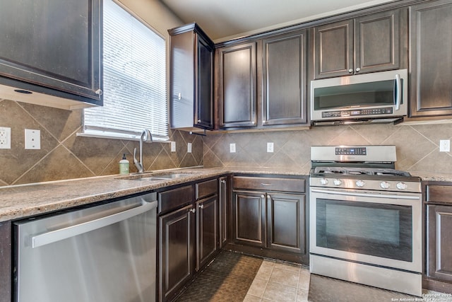kitchen featuring decorative backsplash, a sink, light tile patterned floors, and appliances with stainless steel finishes