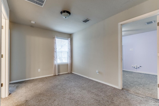 carpeted empty room with baseboards, a textured ceiling, and visible vents