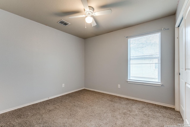 carpeted spare room featuring baseboards, visible vents, and a ceiling fan