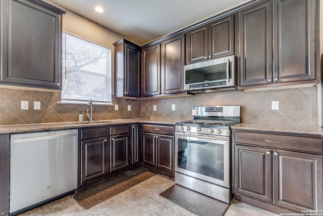kitchen featuring light tile patterned floors, stainless steel appliances, decorative backsplash, light stone counters, and dark brown cabinetry