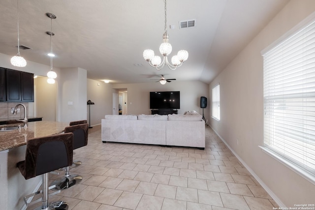 living room with light tile patterned floors, ceiling fan with notable chandelier, baseboards, and visible vents