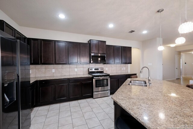 kitchen with decorative backsplash, visible vents, light stone countertops, stainless steel appliances, and a sink