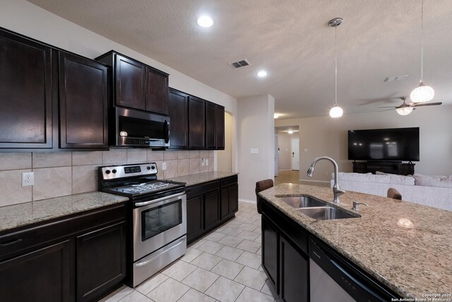 kitchen with open floor plan, decorative light fixtures, decorative backsplash, a sink, and appliances with stainless steel finishes