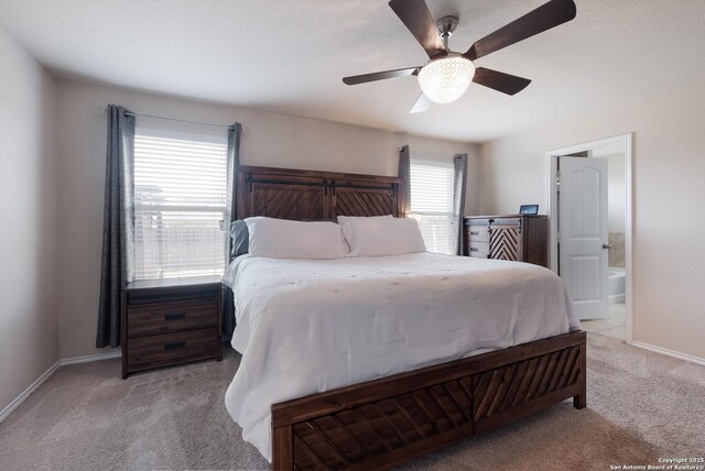 carpeted bedroom with baseboards, ensuite bath, and a ceiling fan