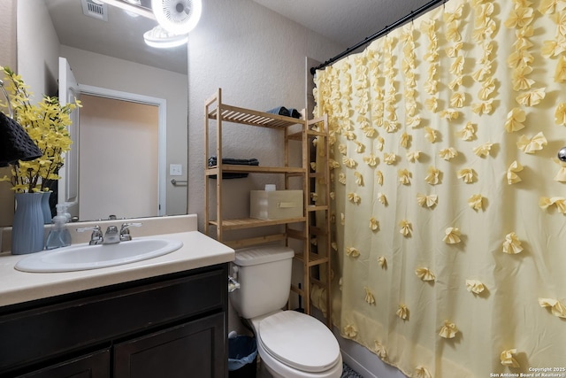 full bathroom featuring visible vents, toilet, curtained shower, vanity, and a textured wall