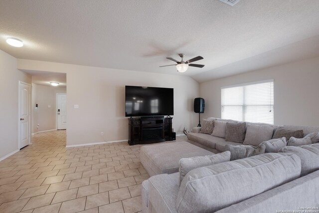 living room featuring vaulted ceiling, light tile patterned floors, baseboards, a textured ceiling, and a ceiling fan