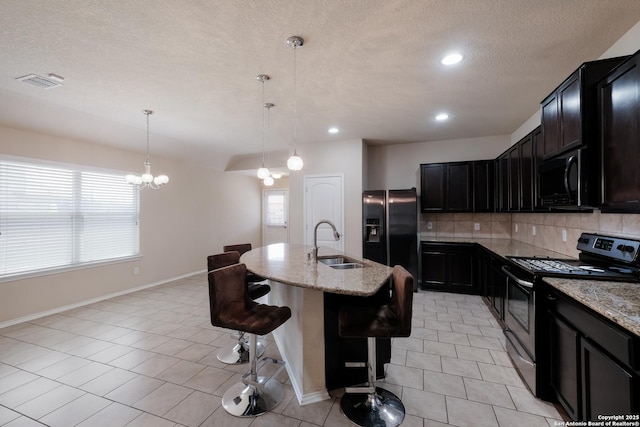 kitchen featuring a sink, black appliances, visible vents, and light stone counters