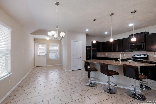 kitchen featuring decorative backsplash, a breakfast bar, dark stone counters, appliances with stainless steel finishes, and a sink