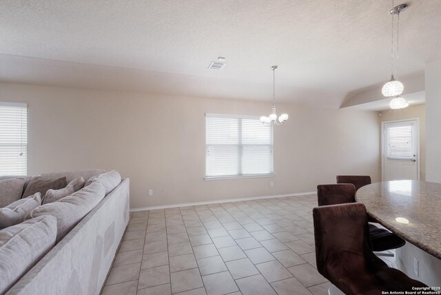living area featuring a wealth of natural light, baseboards, a chandelier, and visible vents
