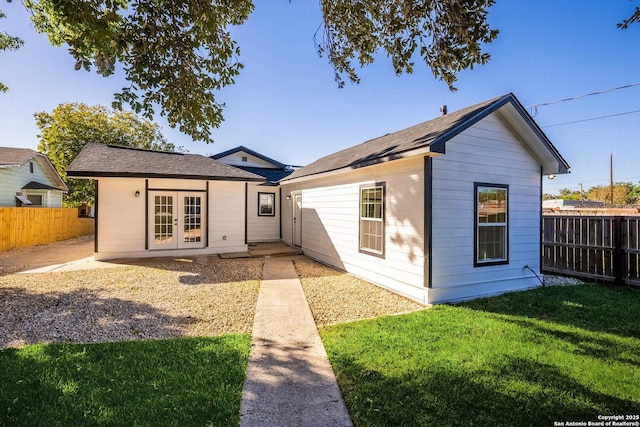 rear view of property featuring an outbuilding, a fenced backyard, french doors, and a yard