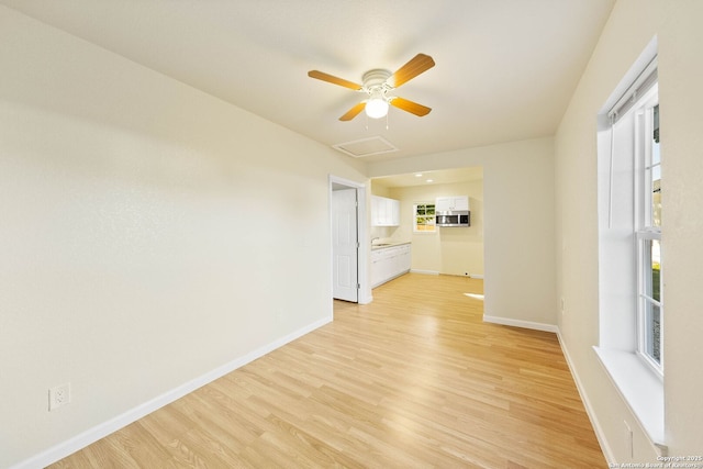 empty room with baseboards, light wood-style floors, and attic access
