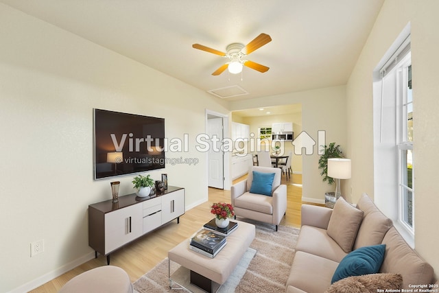 living area featuring baseboards, a ceiling fan, light wood-type flooring, and attic access