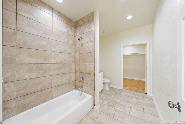 bathroom with tile patterned flooring, a walk in closet, toilet, bathtub / shower combination, and baseboards
