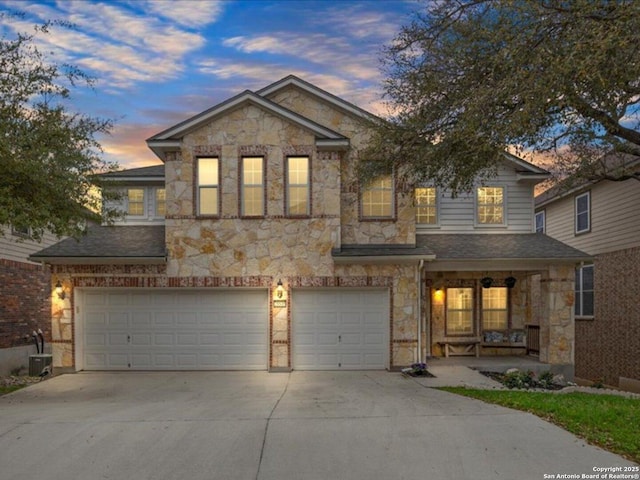 view of front of property featuring stone siding, an attached garage, and driveway