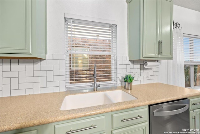 kitchen featuring stainless steel dishwasher, green cabinetry, light countertops, and a sink