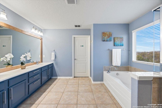 bathroom featuring tile patterned floors, a sink, a garden tub, a textured ceiling, and visible vents