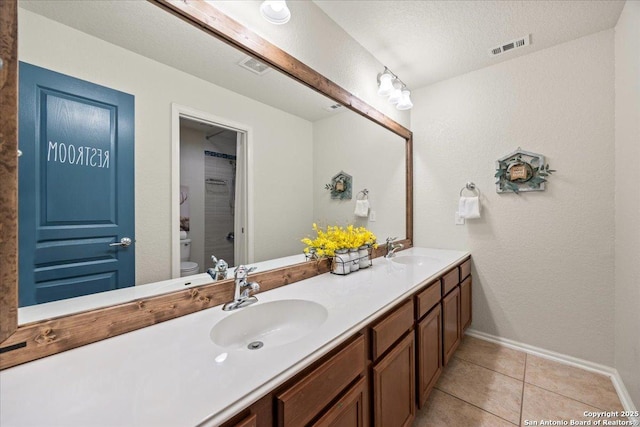 full bath with double vanity, a sink, toilet, and tile patterned floors