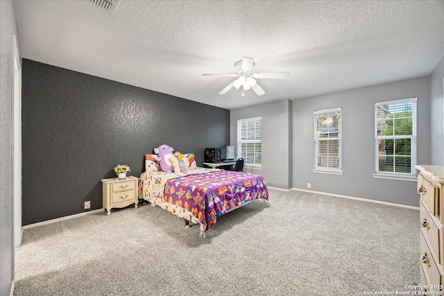 carpeted bedroom featuring a ceiling fan, a textured ceiling, baseboards, visible vents, and a textured wall