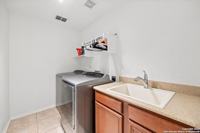 laundry area featuring light tile patterned floors, a sink, washer and clothes dryer, and visible vents