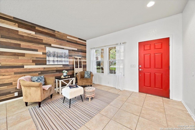 sitting room with wooden walls, baseboards, tile patterned floors, recessed lighting, and an accent wall