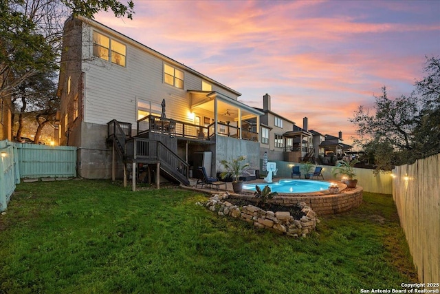 back of house at dusk featuring a fenced backyard, a fenced in pool, stairway, and a yard