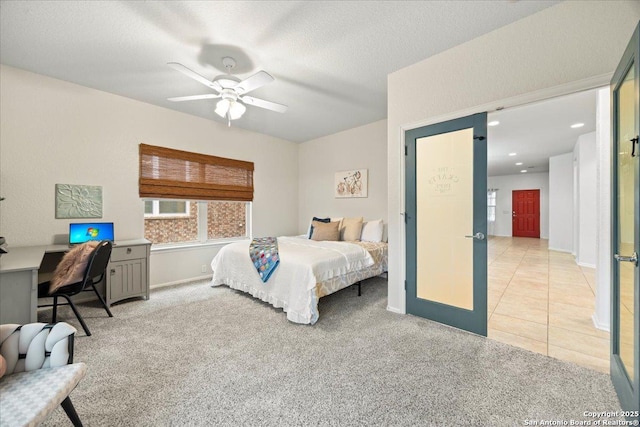 bedroom featuring a ceiling fan, light tile patterned floors, light colored carpet, and a textured ceiling