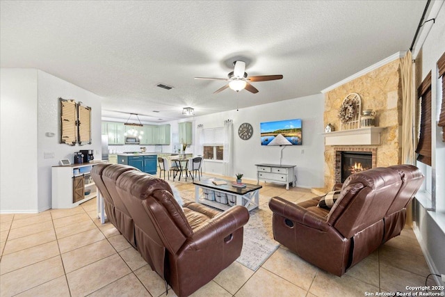 living area featuring a textured ceiling, a fireplace, light tile patterned floors, and a ceiling fan