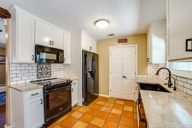 kitchen with a sink, visible vents, white cabinetry, and black appliances
