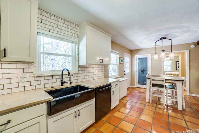 kitchen featuring white cabinets, dishwasher, tasteful backsplash, a sink, and hanging light fixtures