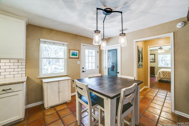 tiled dining area featuring plenty of natural light, baseboards, a textured wall, and a textured ceiling
