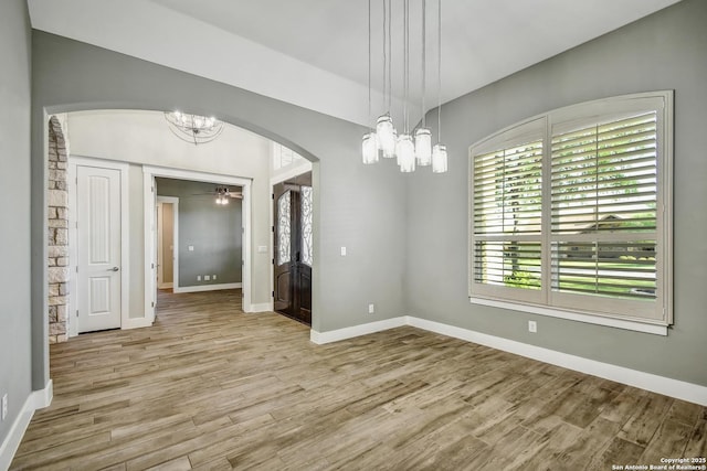 1609 Havenwood, New Braunfels, TX 78132 - unfurnished room featuring arched walkways, baseboards, wood finished floors, and ceiling fan with notable chandelier
