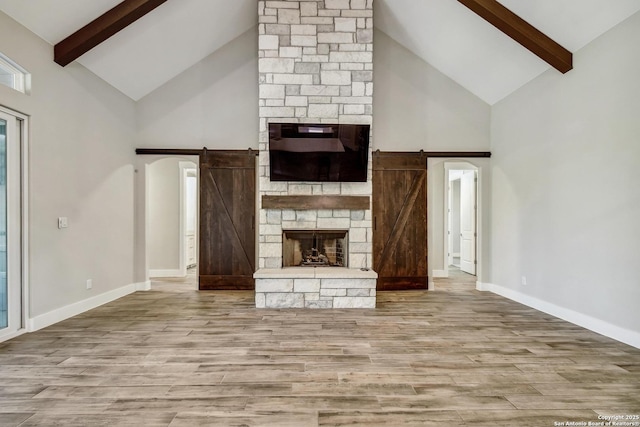 1609 Havenwood, New Braunfels, TX 78132 - unfurnished living room with beam ceiling, a fireplace, a barn door, wood finished floors, and baseboards