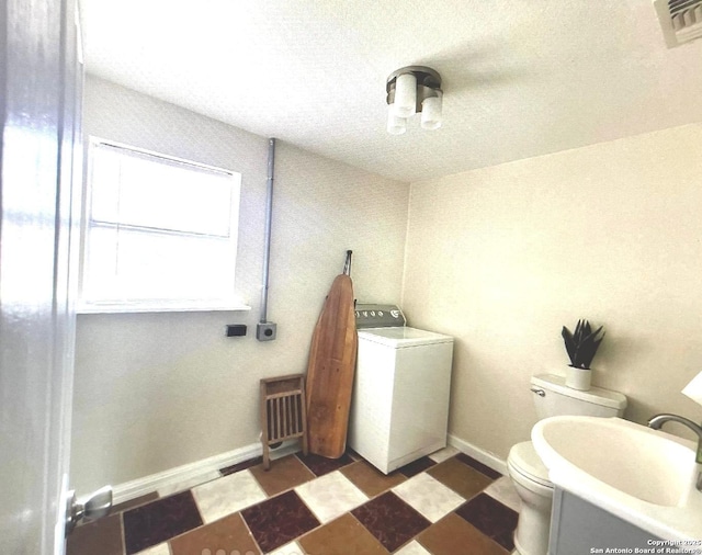bathroom with a sink, washer / dryer, toilet, visible vents, and a textured ceiling