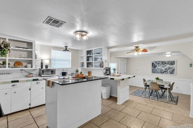 kitchen with visible vents, open shelves, white cabinets, and a center island