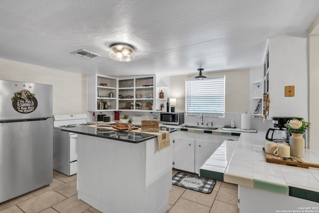 kitchen with open shelves, a sink, visible vents, stainless steel appliances, and tile countertops