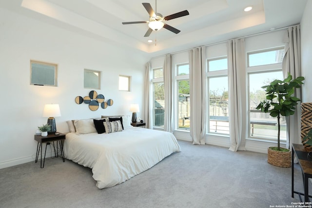bedroom with a tray ceiling, multiple windows, baseboards, and carpet