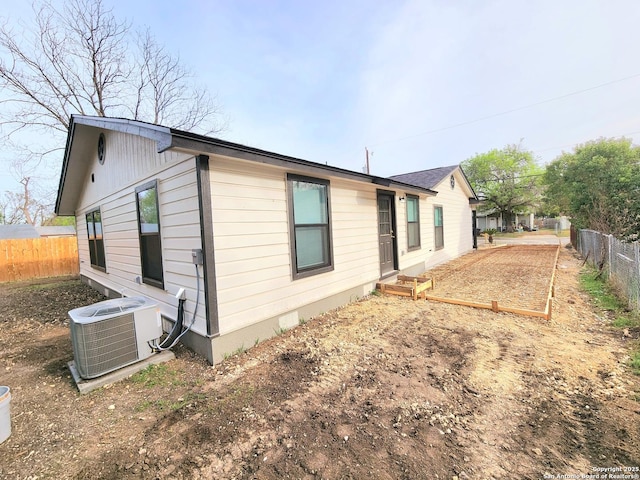 rear view of house with cooling unit and fence