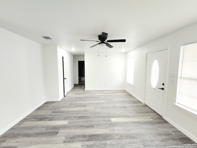 entryway featuring baseboards, visible vents, wood finished floors, and a ceiling fan