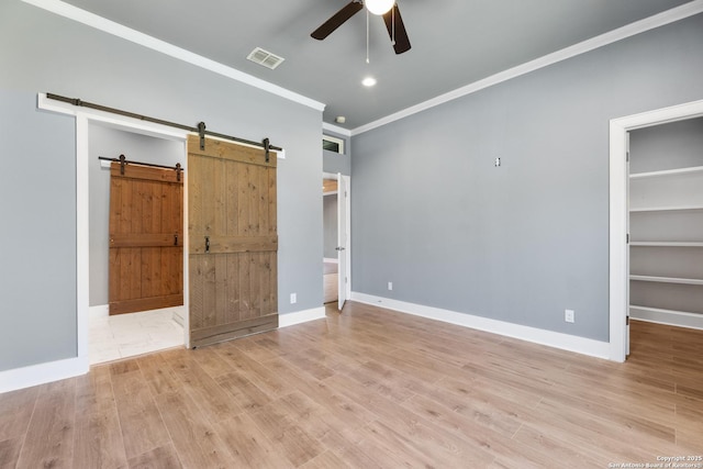 129 Cincinnati, San Antonio, TX 78201 - unfurnished bedroom with visible vents, crown molding, wood finished floors, a barn door, and a spacious closet