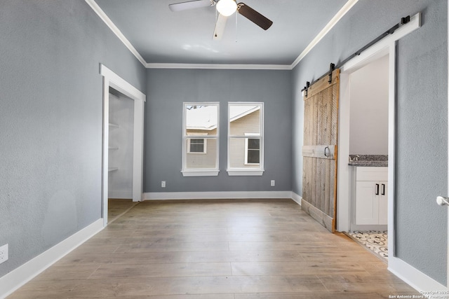 129 Cincinnati, San Antonio, TX 78201 - unfurnished bedroom with baseboards, a barn door, ornamental molding, and wood finished floors