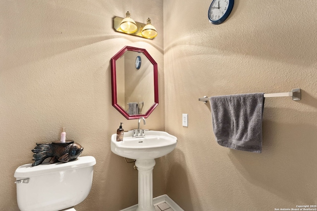 bathroom featuring toilet and a textured wall