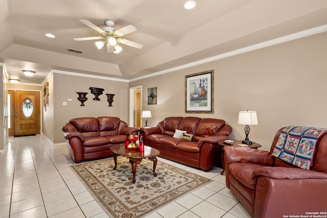living area featuring a raised ceiling, light tile patterned flooring, crown molding, and visible vents