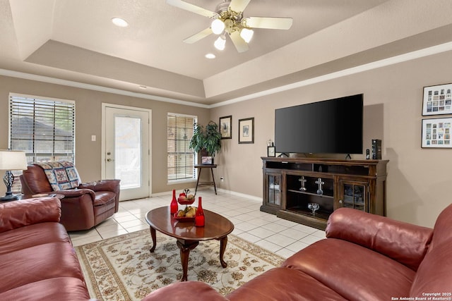 living room featuring light tile patterned flooring, ceiling fan, crown molding, and a raised ceiling