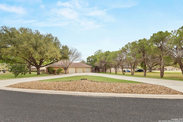 view of front of property featuring a front yard, concrete driveway, and a garage